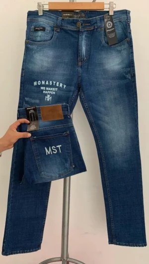 Jean Premium de alta calidad para hombre, corte moderno, color azul medio con sublimado Monastery en pierna derecha, bordados en el monedero y en bolsillo trasero