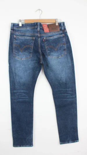 Jean Premium de alta calidad para hombre, corte moderno, color azul medio con bigotes, desgastes pines y botón contramarcado